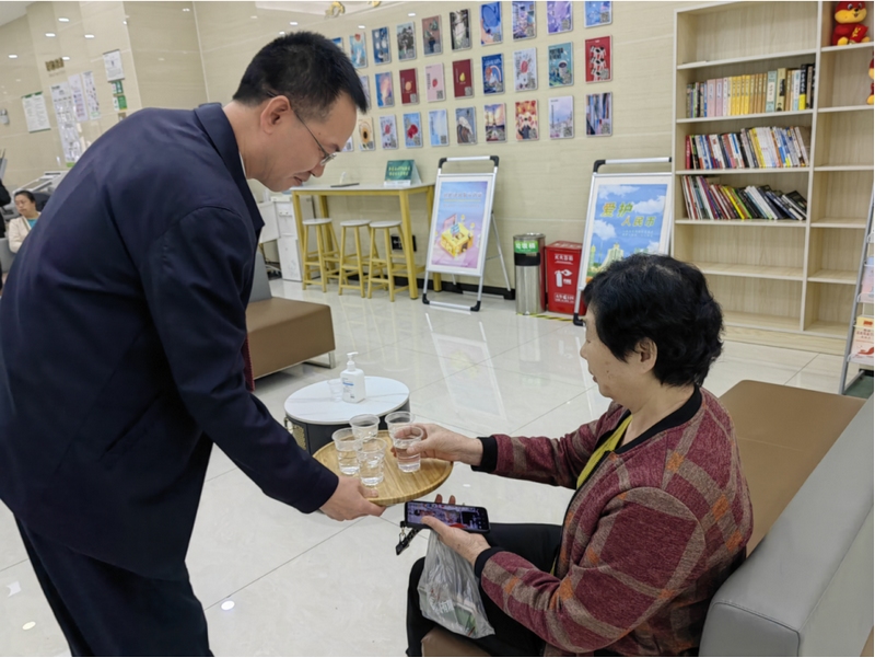 党委书记、董事长王刚在厅堂为客户提供“一杯水”服务。