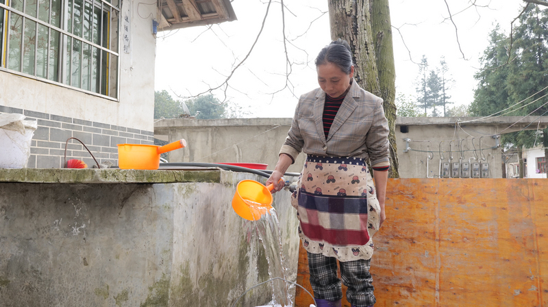 海坝村村民正在自己家院子里取水。