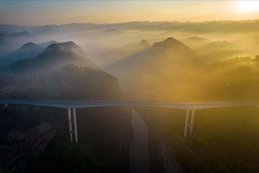 11月28日清晨，貴畢公路六廣河特大橋與雲海、山川交相輝映，構成一幅壯美的交通畫卷。
