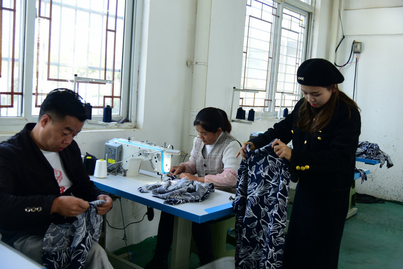 坪子社区服装厂里，居民王发敏（中）正在缝制衣服。汪沙摄