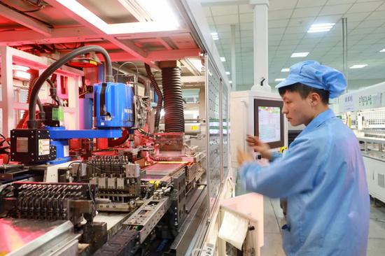 图片贵州一道长通新能源有限公司生产车间内，工人通过电脑检修流水线机器。赵庆能摄
