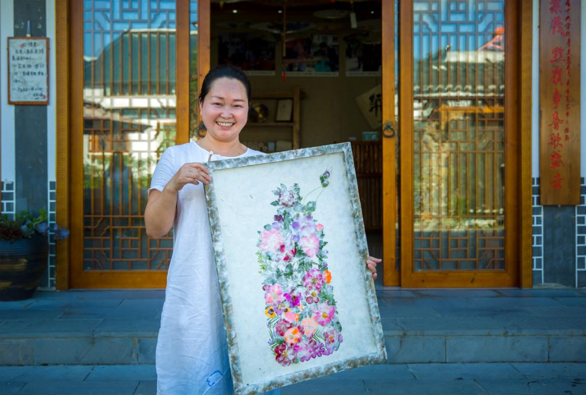 张胜迪向游客展示纸浆画艺术制品。