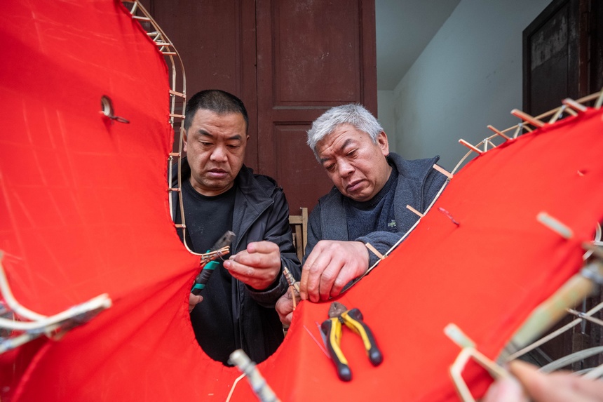 包全（右）在編織竹龍。