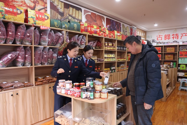 图为该局工作人员向古彝特产店老板刘鑫了解该店生产经营情况。漆毓摄