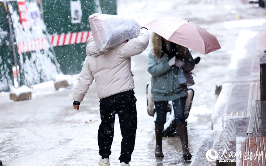 行人扛着袋子在雪中行走。人民网 顾兰云摄