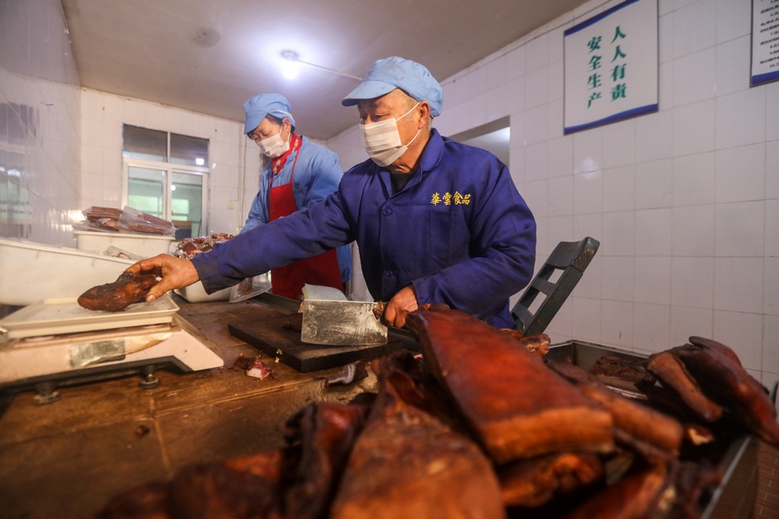 2024年1月19日，工人在贵州省黔东南苗族侗族自治州施秉县一家腊肉加工企业车间包装腊肉。