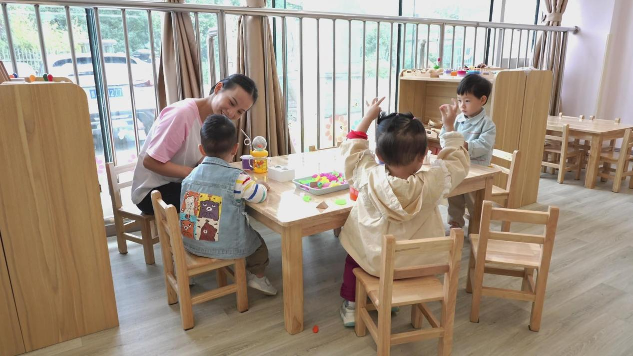 贵阳市妇幼保健院附属托育中心老师和孩子们做益智游戏。