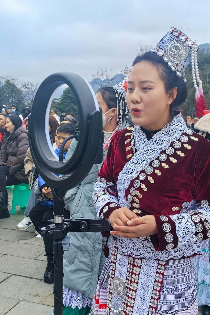 台下的老乡们纷纷掏出手机拍摄转发，让许多外地人通过网络也看到了化屋的美丽山水、民俗文化。图为95后绣娘杨文丽正在直播“村晚”现场。程焕摄