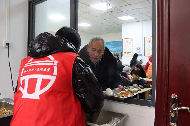 志愿者帮忙打饭菜。