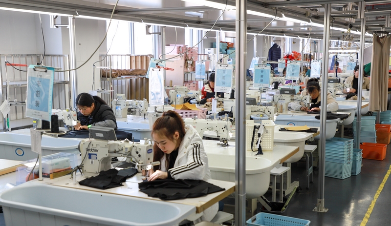 2月18日，在貴州星美服飾有限公司生產車間，工人們正忙著裁邊、縫線、熨燙等工作，一如往日的忙碌景象。（路小榕攝