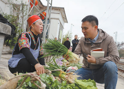 图为程焕（右）在采访准备搭车进城卖菜的群众。