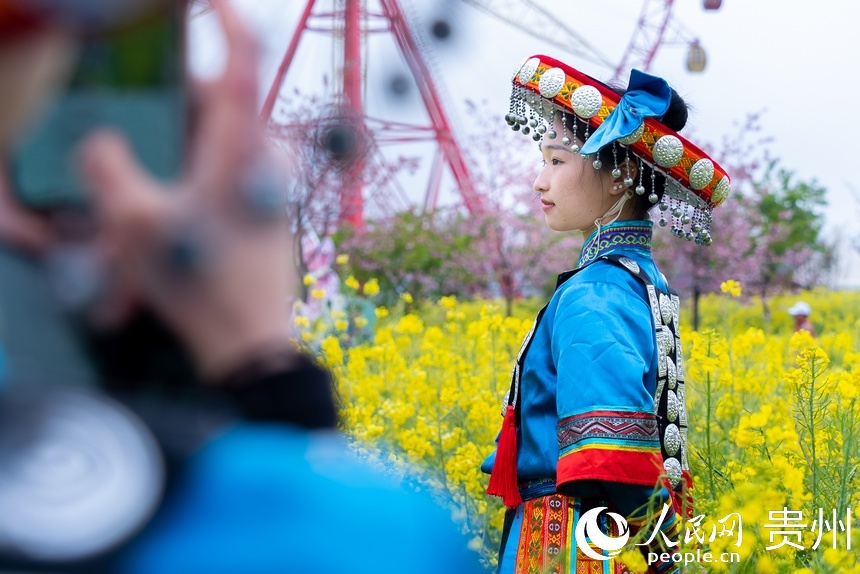 身着少数民族服饰的姑娘在油菜花中拍照。人民网记者 涂敏摄