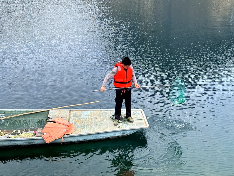 邓志文打捞湖面上的垃圾。