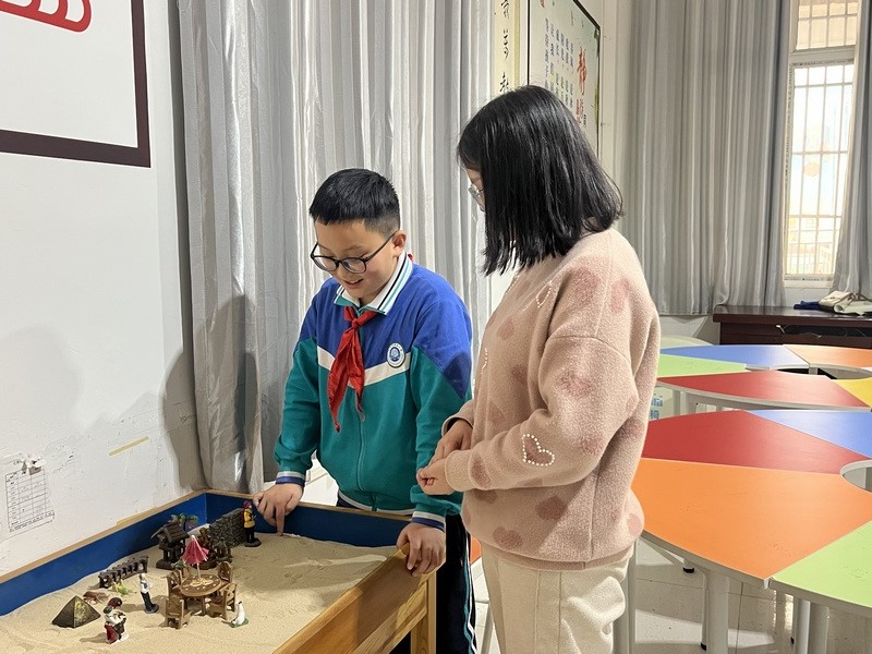 老师陪学生玩沙盘游戏。