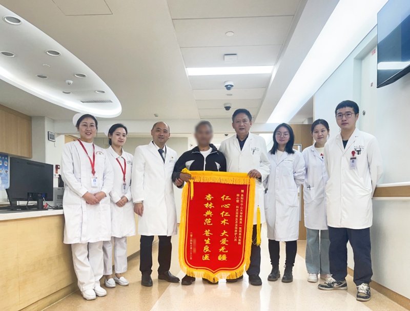 患者手持锦旗与医护人员合影。
