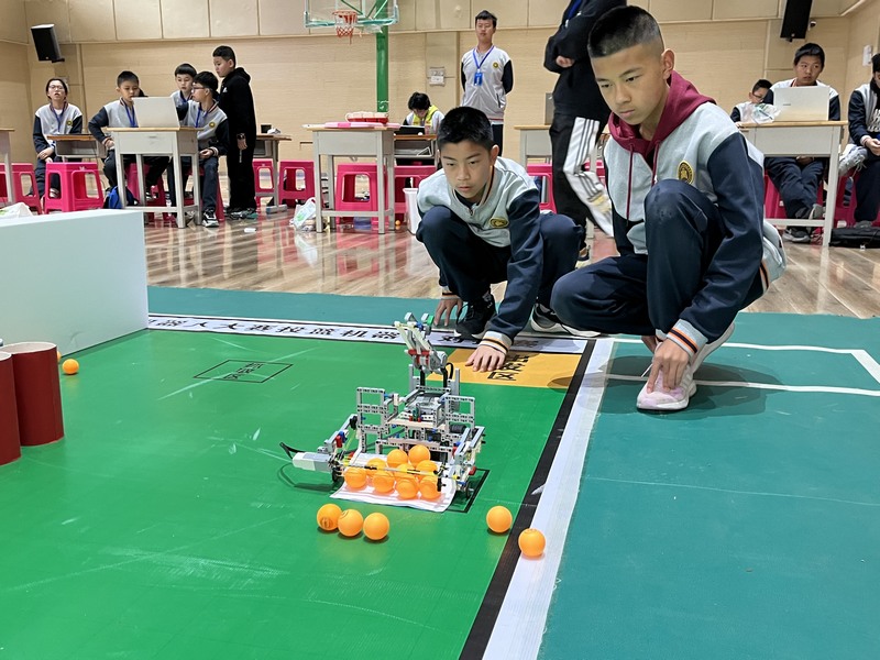 兩名參賽隊員用自制“機器人”抓乒乓球。
