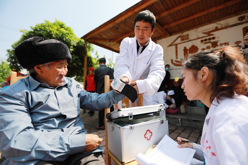 医务人员和志愿者在贵州省黔西市林泉镇敬老院为老人量血压、测血糖。