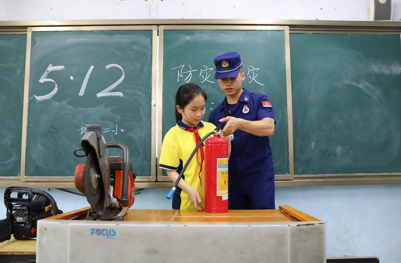 图为消防员正在指导学生使用灭火器。杨洁茹摄