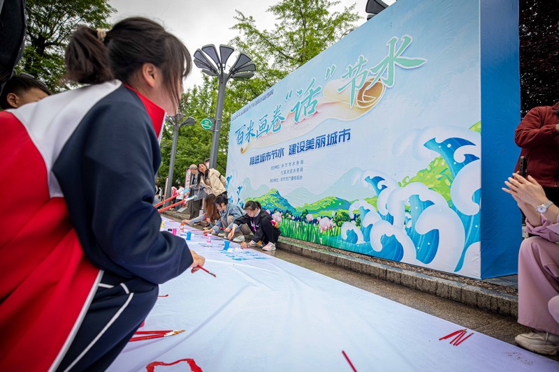 2024年5月11日,人们在贵州省毕节市人民公园里共同绘制“百米长卷节水图”。