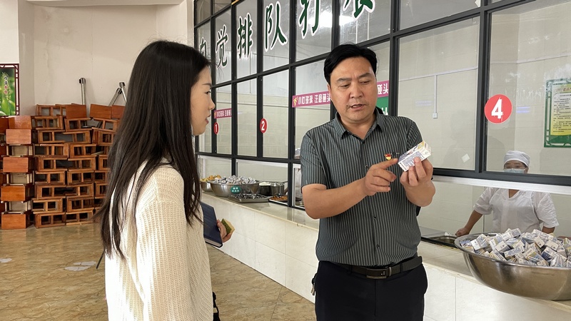 三合鎮第一小學副校長正向工作人員介紹學生特供牛奶  攝影廖祝梅.jpg