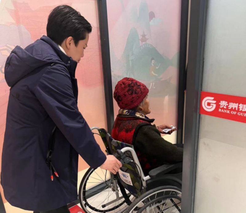 吴卉使用网点的轮椅车推行动不便的老人。