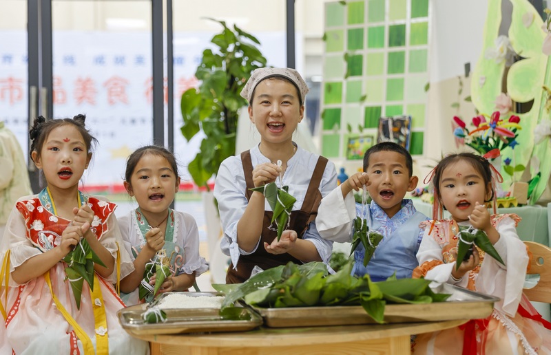 6月7日，在贵州省黔东南苗族侗族自治州施秉县第四幼儿园，老师和小朋友展示刚包的粽子。磨桂宾摄