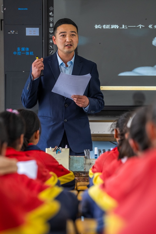 在毕节市威宁自治县双龙镇凉山小学，一名老师正在给孩子们上名为《金色的鱼钩》的语文课，文中的主人公原型为参加红军长征的当地人。