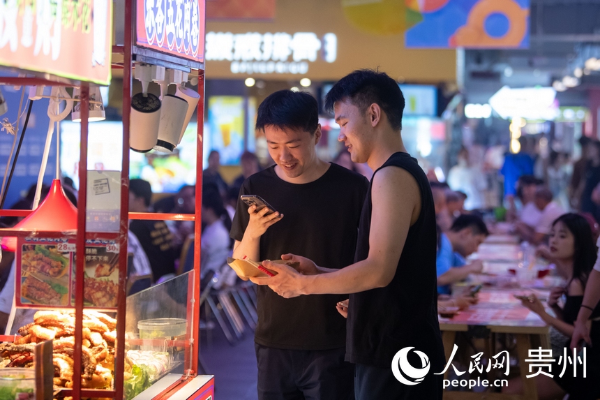 6月21日，在青云市集内，游客正用手机拍摄美食。人民网记者 翁奇羽摄