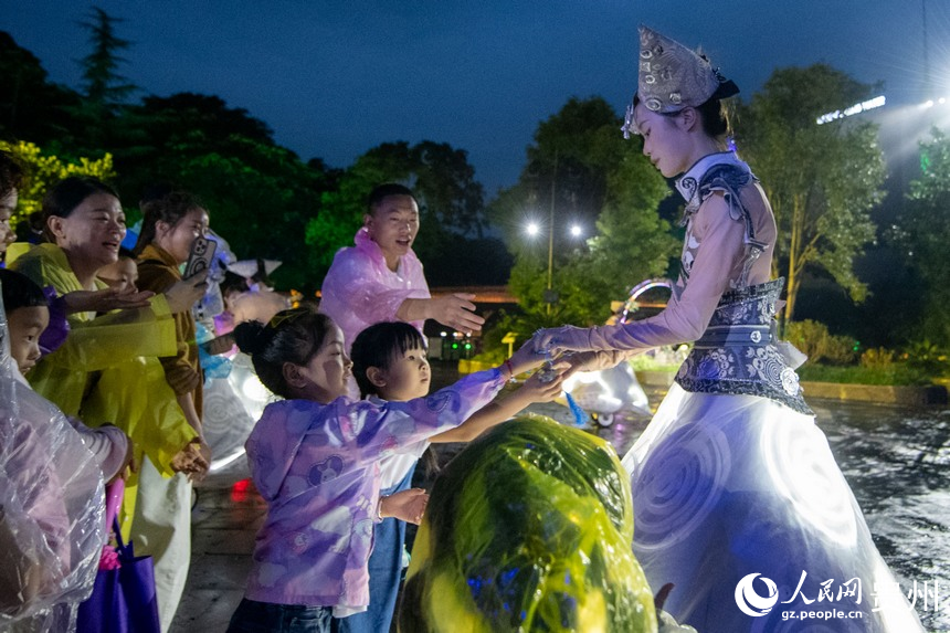 6月23日，游客夜游黄果树瀑布，与表演人员互动。人民网记者 翁奇羽摄