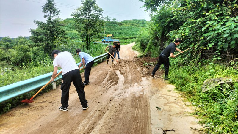 图为：和平村村工作人员积极清理道路泥土障碍