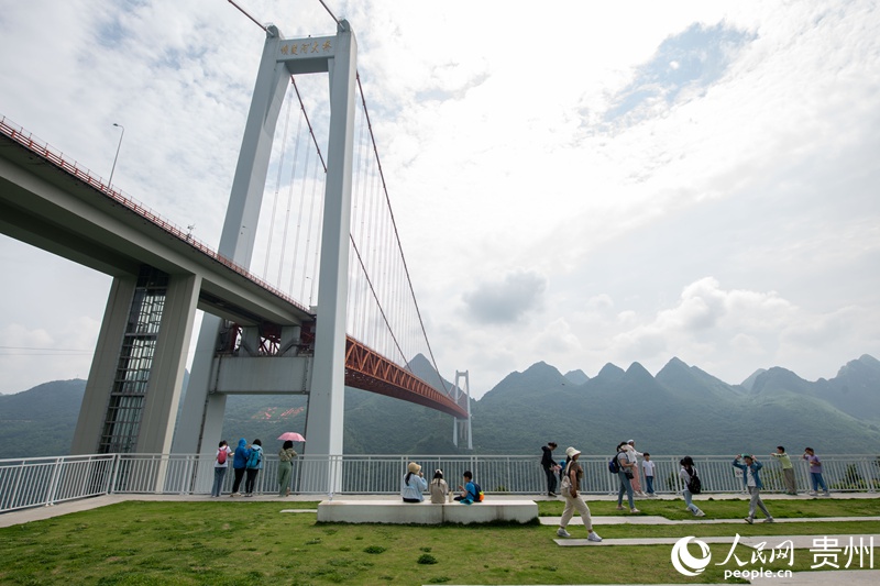 在坝陵河大桥下，游客正在拍照打卡。人民网记者 翁奇羽摄