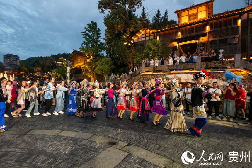 6月24日，在乌江寨景区，传统民俗表演吸引众多游客参与互动。人民网记者 翁奇羽摄