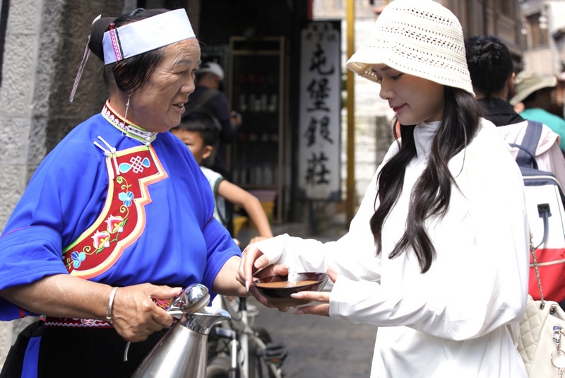 1 圖為7月23日，安順天龍屯堡內，一位穿著傳統服裝的居民為游客倒茶。  王玨瑋 攝