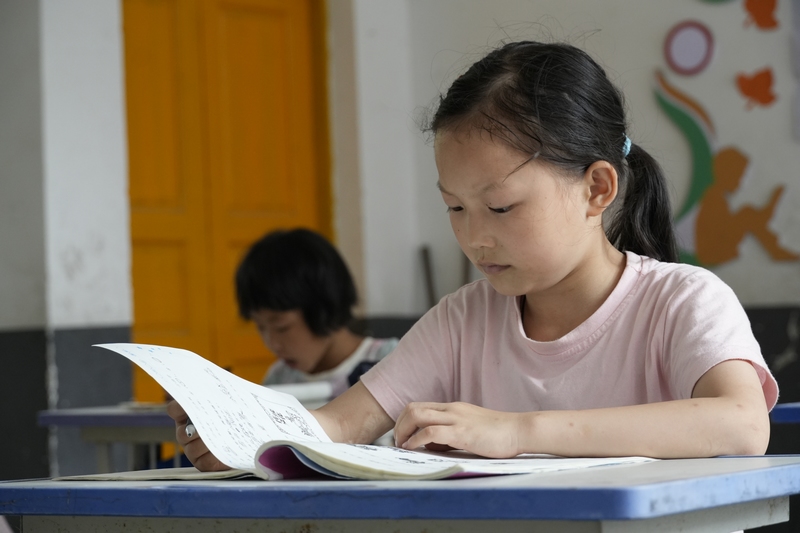 大河坝镇酸汤小学的大学生志愿者正在辅导孩子们。