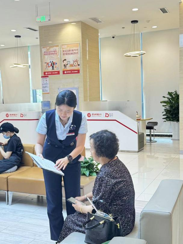 图为贵州银行铜仁分行网点工作人员为老年客户介绍产品。