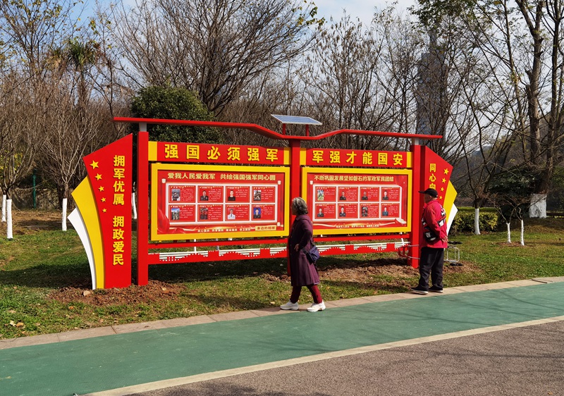 观山湖区公园晨练市民观看现役军人先进事迹展牌。