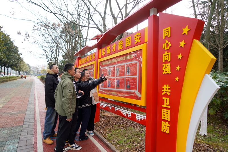 适龄青年在宣传专栏前观看学习现役军人先进事迹。