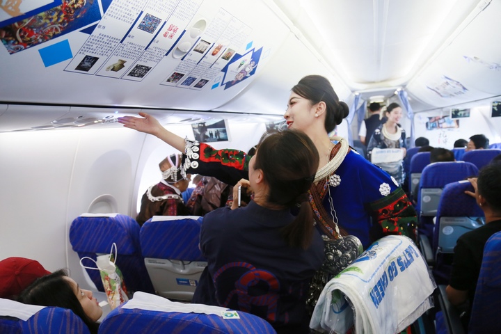 乘务员为旅客讲解非物质文化遗产海报。南航贵州公司供图