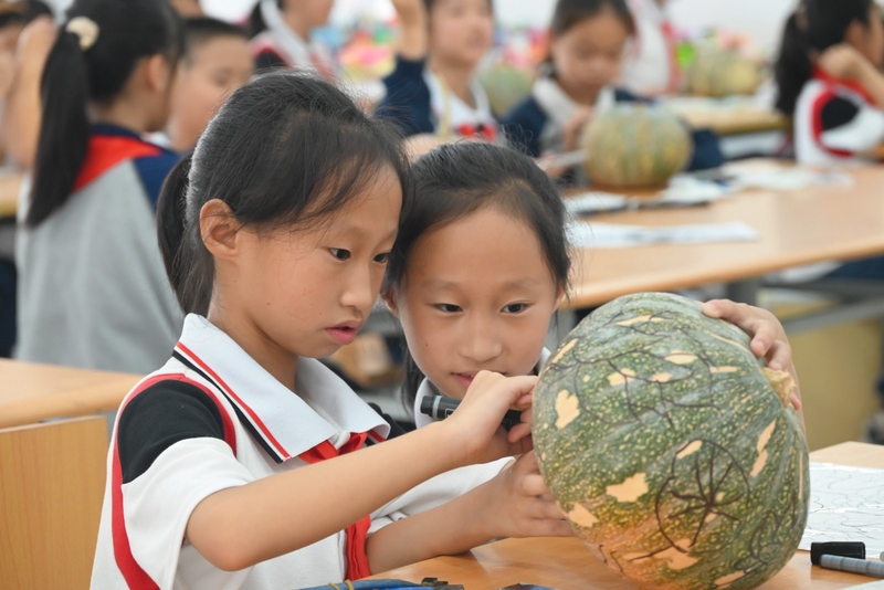 清镇市时光实验学校学生在南瓜上绘图。沈建华 摄