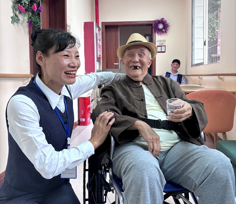87岁的袁正大老人和工作人员一起聊天，脸上洋溢着笑容