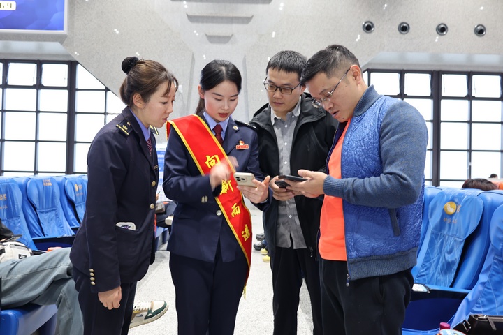 在高铁站候车大厅，铁路+税务联合服务团队向旅客宣传“电子客票”并辅导开具。何博摄