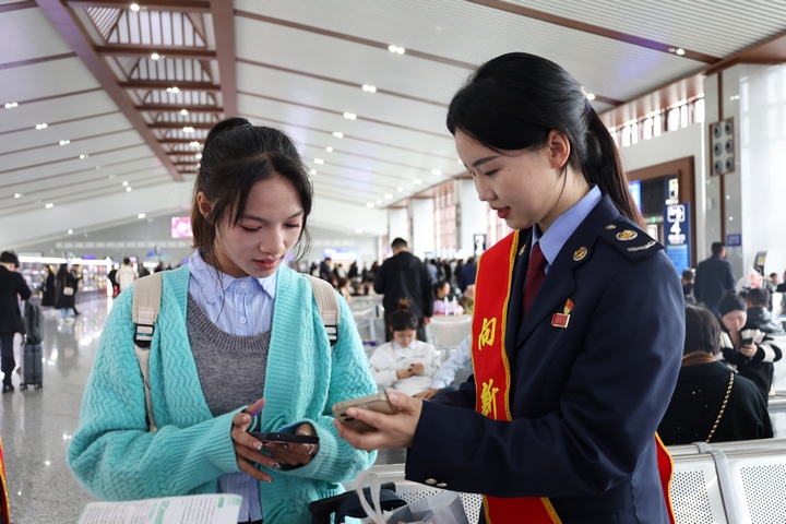 在高铁站候车大厅税务干部向旅客宣传“电子客票”并辅导开具。何博摄