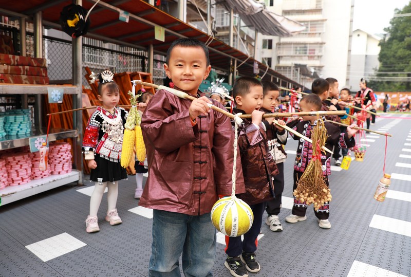 在剑河县城关第二幼儿园，小朋友们挑着年礼游行展示。