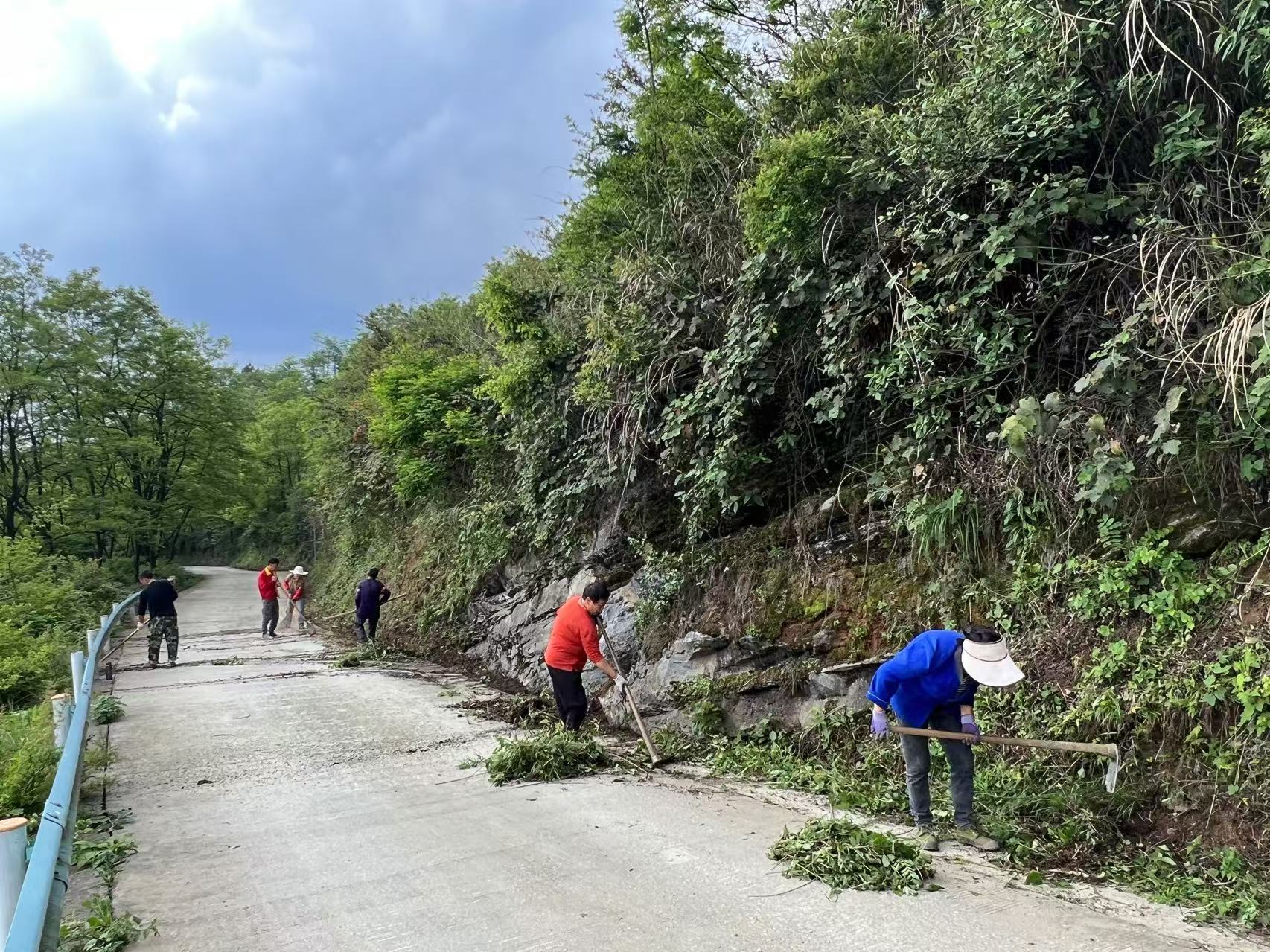 干部群众齐心清理路边垃圾。