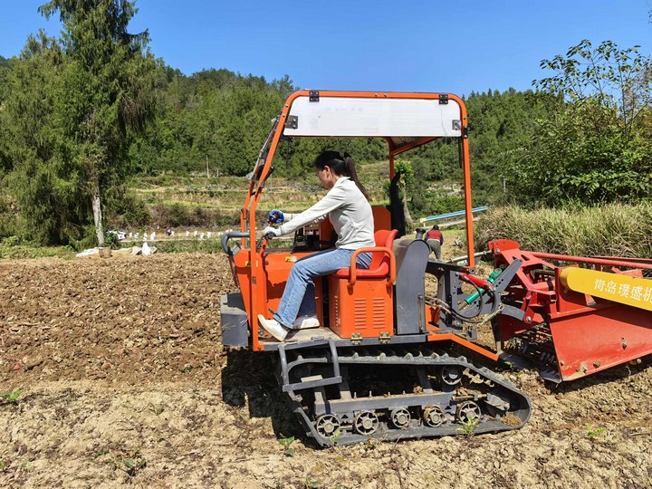 村民駕駛農機在田間作業。