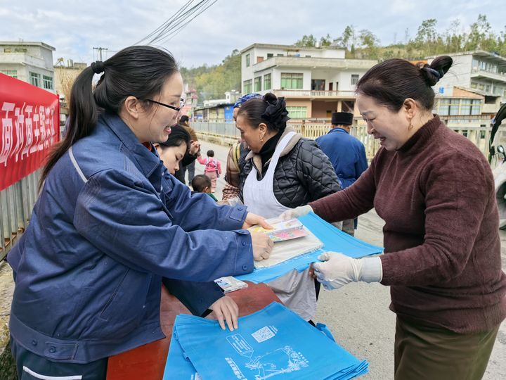 工作人员正在向赶集的村民发放安全用电宣传册。.jpg