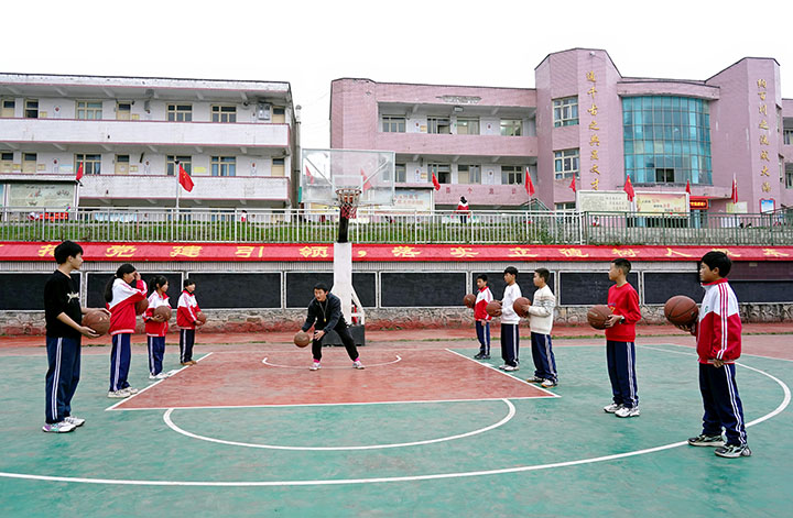 篮球社团老师在给学生示范拍球。