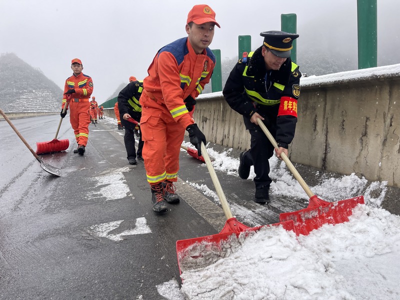 交通执法人员与消防人员共同对路面积雪进行清除。