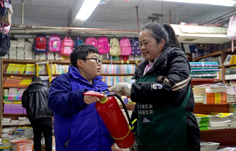 2025年2月17日，贵州省毕节市纳雍县城一书店，检查组成员在指导书店员工使用灭火器。杨英摄