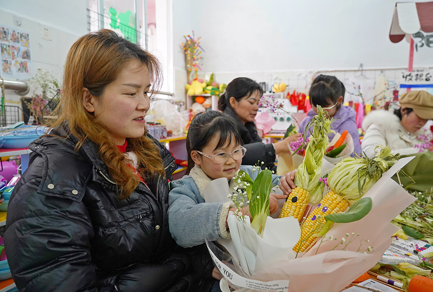 2025年3月6日，贵州省毕节市纳雍县龙场镇中心幼儿园“温情三八·感恩有您”活动现场，家长和孩子们一起做手工。  杨  英 摄